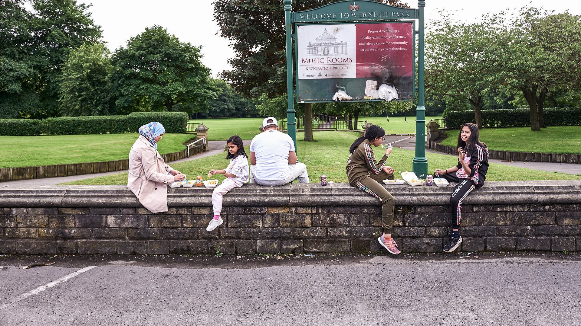 Family group sitting on a wall in a park