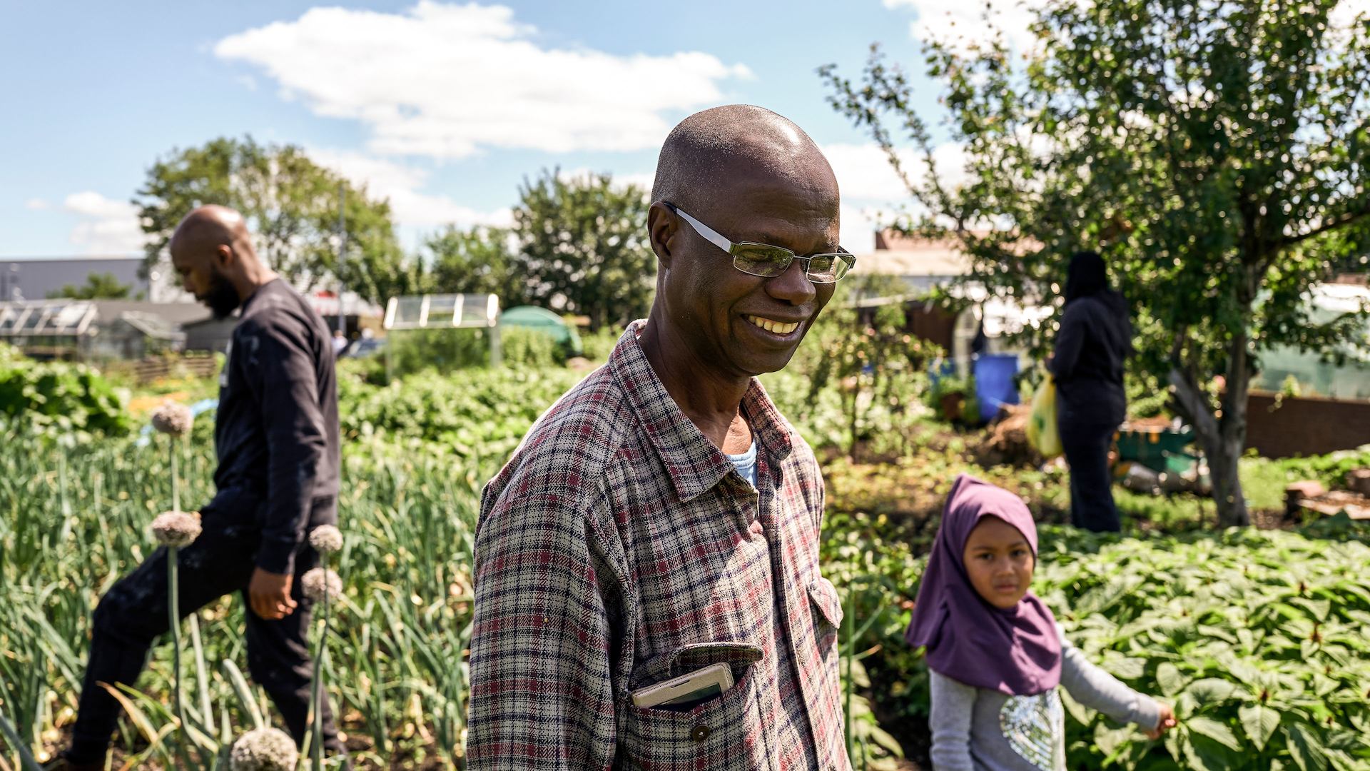 Man approaching later life outside in an allotment with friends