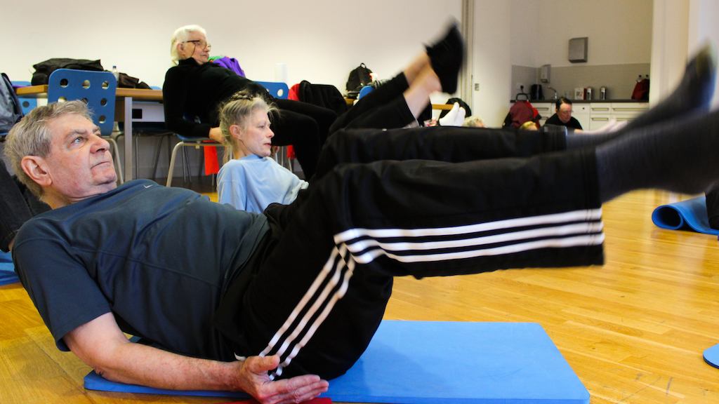 Pupils in a physio yogalates class doing a balancing rocking pose.