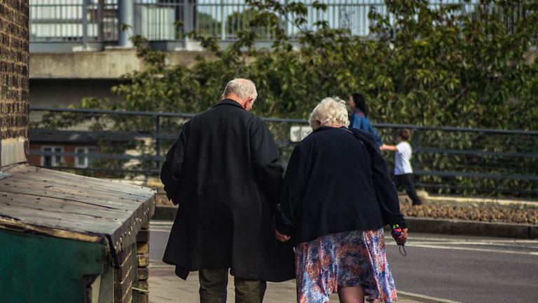 Elderly couple seen walking from behind.