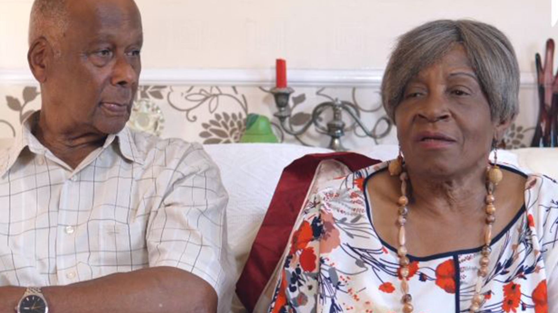 Elderly black couple sitting on sofa at home.