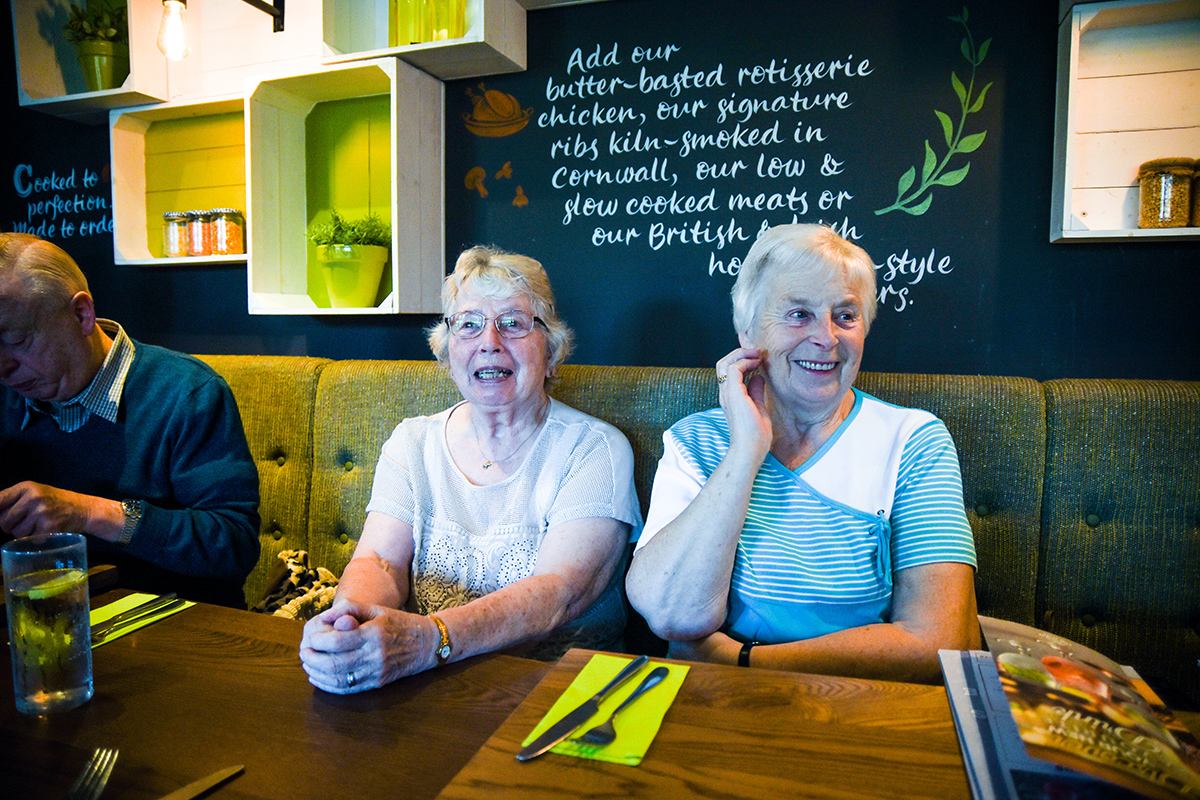 Two older ladies at a table sharing a laugh