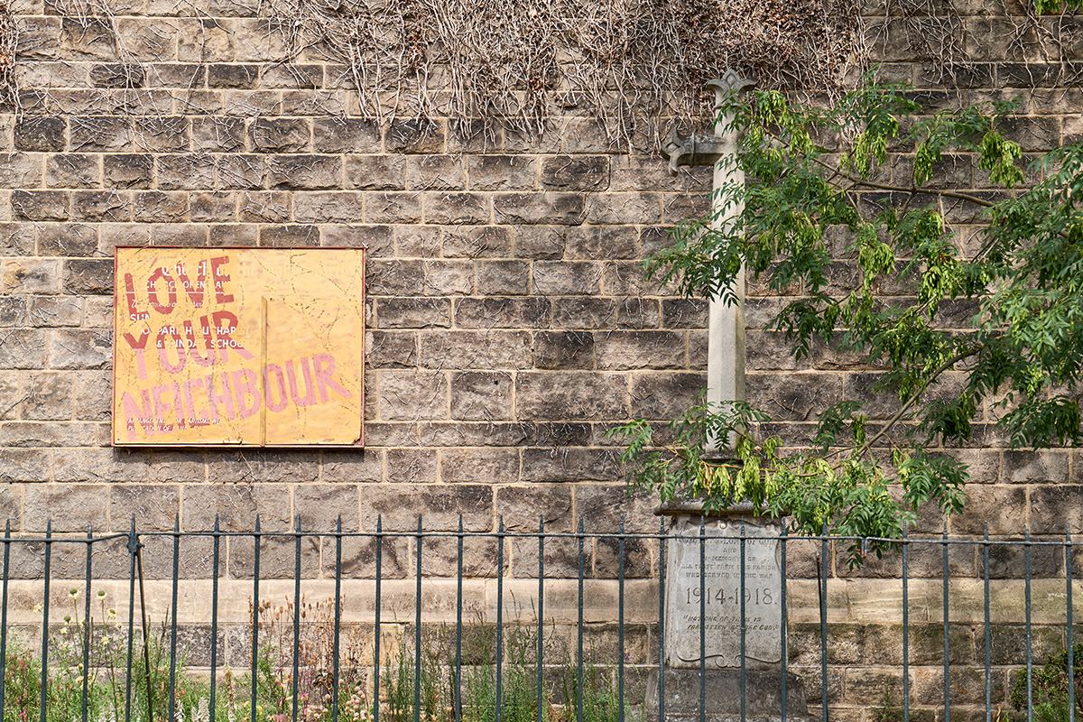Brick wall with 'love your neighbour' sign.